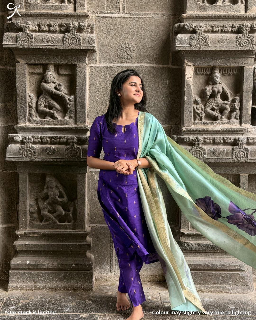 Woman wearing violet raw silk salwar set with pastel muslin dupatta near temple wall