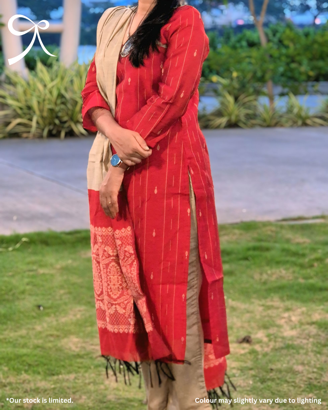 Person wearing a red traditional outfit with a beige scarf in an outdoor setting.